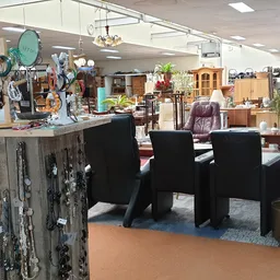 Winkelinterieur met zwarte stoelen, decoratieve objecten op stellingen en diverse meubels en huishoudartikelen