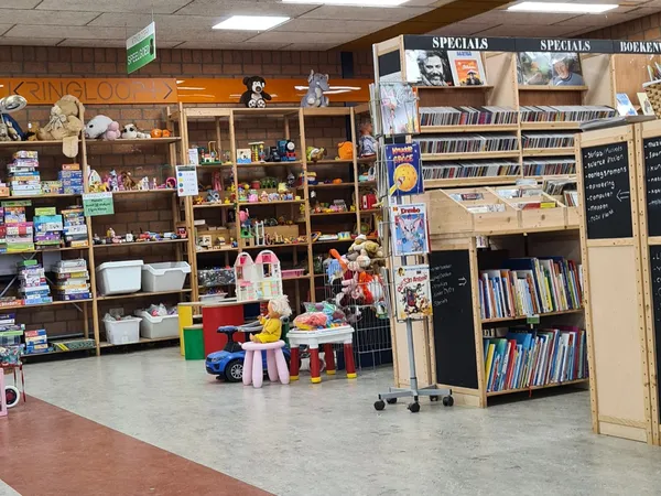 Winkelvloer met stellingen vol speelgoed, kindermeubels en boeken in een kringloopwinkel