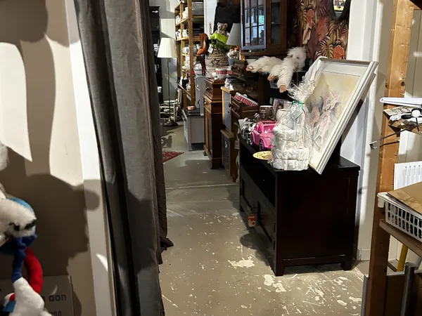 Smalle gangpad in kringloopwinkel met stellingen vol kleding en spullen aan beide zijden