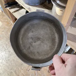 Close-up van een grijze metalen pan of pot met gebarsten glazuurlaag