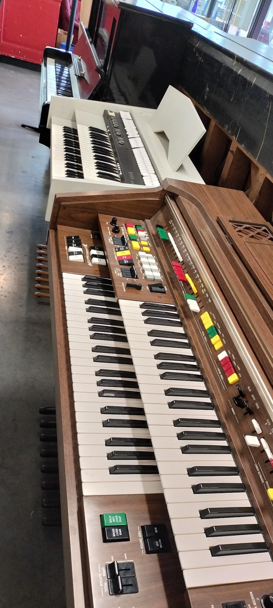 Vintage synthesizer met toetsenbord, knoppen en gekleurde faders op houten voet