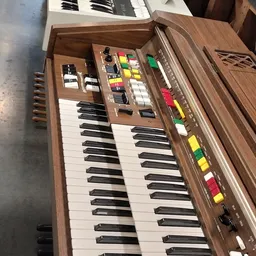 Vintage synthesizer met toetsenbord, knoppen en gekleurde faders op houten voet