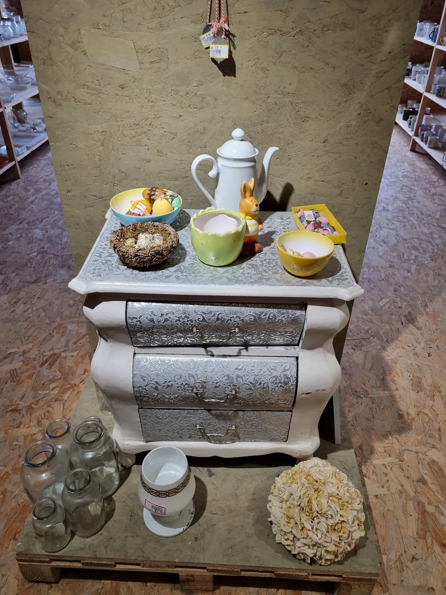 Vintage dressoir met drie laden en decoratieve serviesgoed erop, inclusief theepot en kandelaars