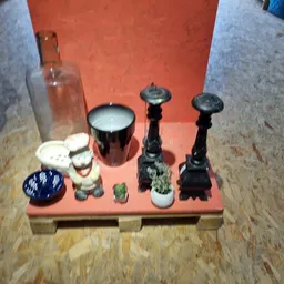 Verschillende decoratieve items op oranje ondergrond: porseleinenfiguurtjes, kandelaars, kopje en schaaltje