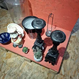 Verzameling tweedehands huishoudartikelen op rode ondergrond: plantenpotten, decoratieve objecten en keukenapparatuur
