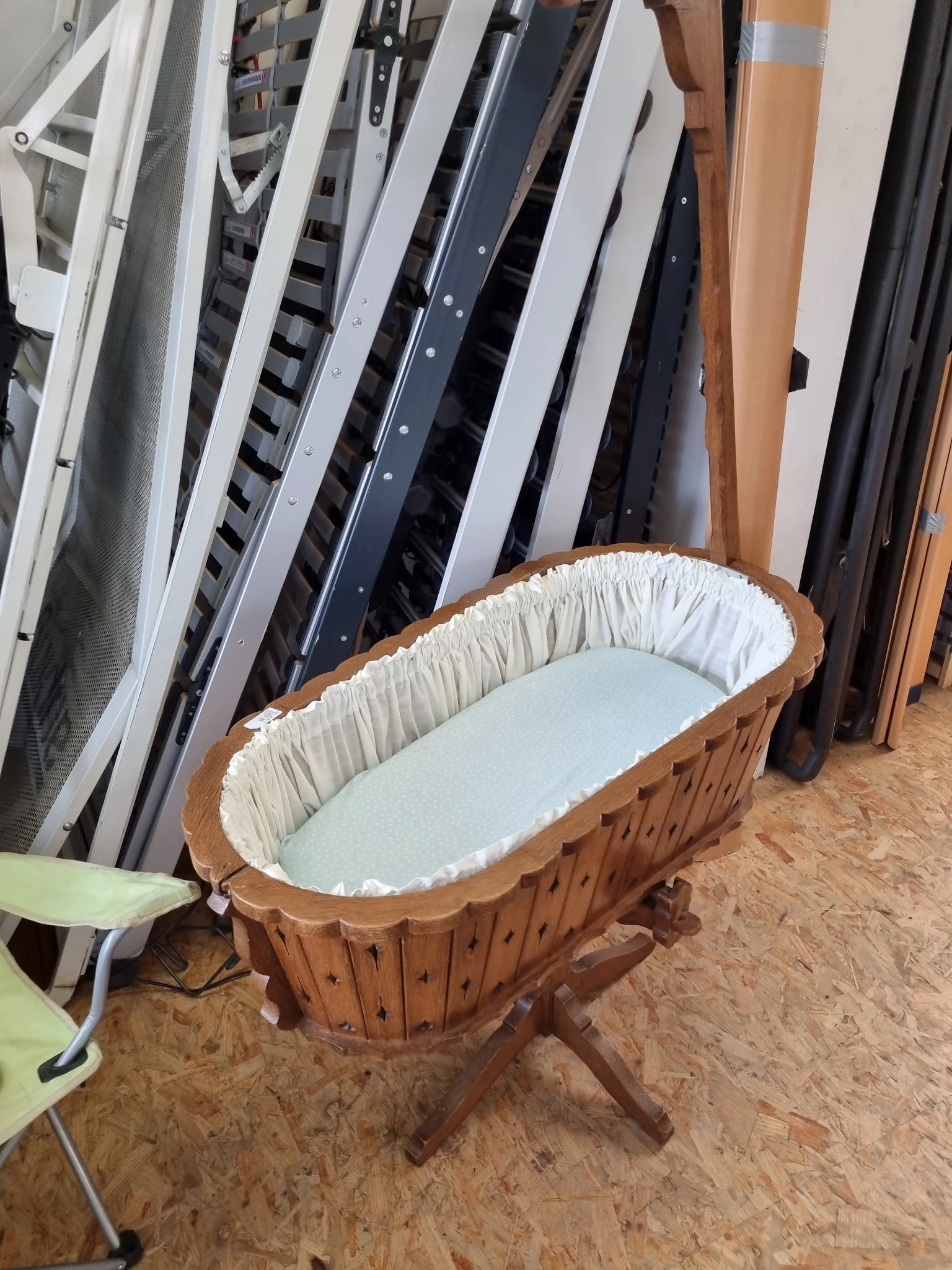 Houten babybedje met witte binnenkant in opslag tussen andere meubels
