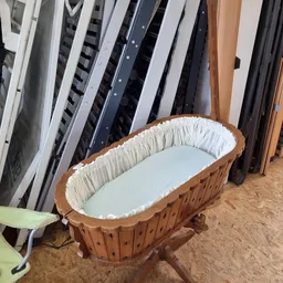 Houten babybedje met witte binnenkant in opslag tussen andere meubels