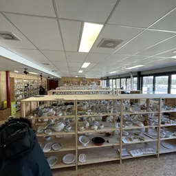 Houten stellingen met aardewerk, servies en huishoudelijke artikelen in de kringloopwinkel