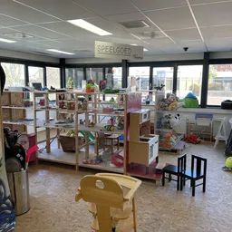 Winkelvloer met stellingen vol speelgoed, boeken en andere artikelen, grote ramen aan de voorkant