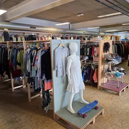Winkelvloer met kledingrekken, etalagepoppen en uiteenlopend aanbod van tweedehands kleding