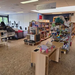 Winkelvloer met stellingen vol speelgoed, boeken en gebruiksartikelen in een kringloopwinkel