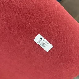 Witte prijssticker op rode stoffen ondergrond
