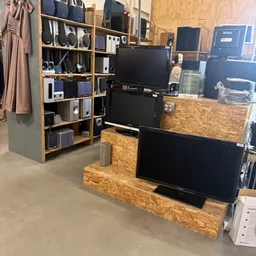 Uitgestalde televisies en elektronische apparatuur op houten stellingen in de winkel