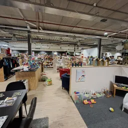 Overzicht van winkelruimte met stellingen, tafels met spullen, kleding en diverse artikelen