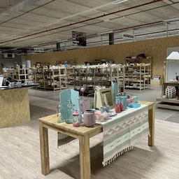 Ruime winkelvloer met houten toonbank en display met huishoudelijke artikelen, op achtergrond stellingen met meubels en inric