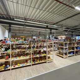 Overzicht van de winkelvloer met houten stellingen vol speelgoed, poppen en diverse tweedehands artikelen