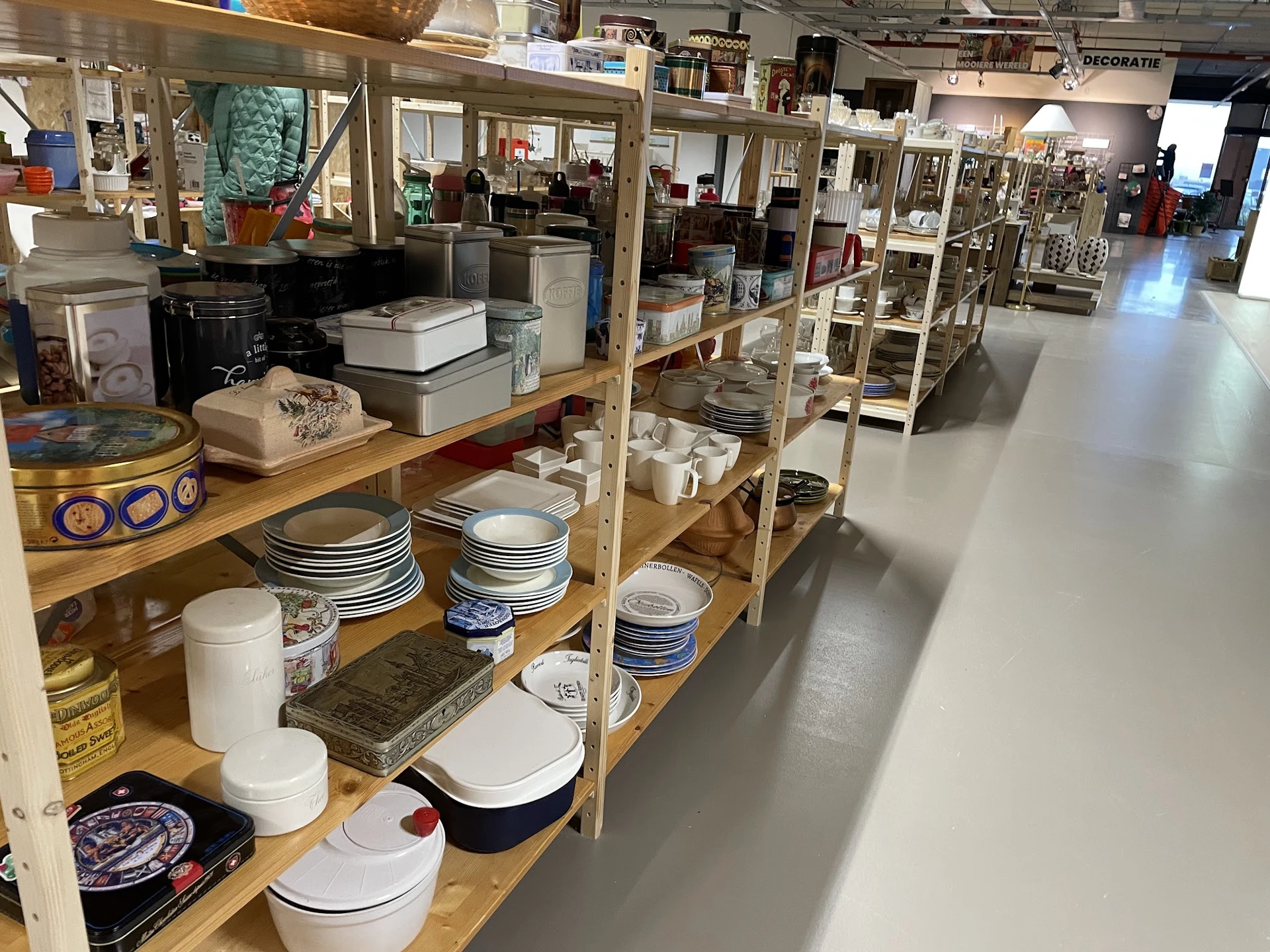 Houten stellingen met servies, borden, schalen en keukengerei in de kringloopwinkel