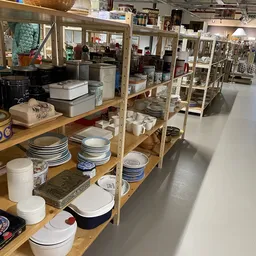 Houten stellingen met servies, borden, schalen en keukengerei in de kringloopwinkel