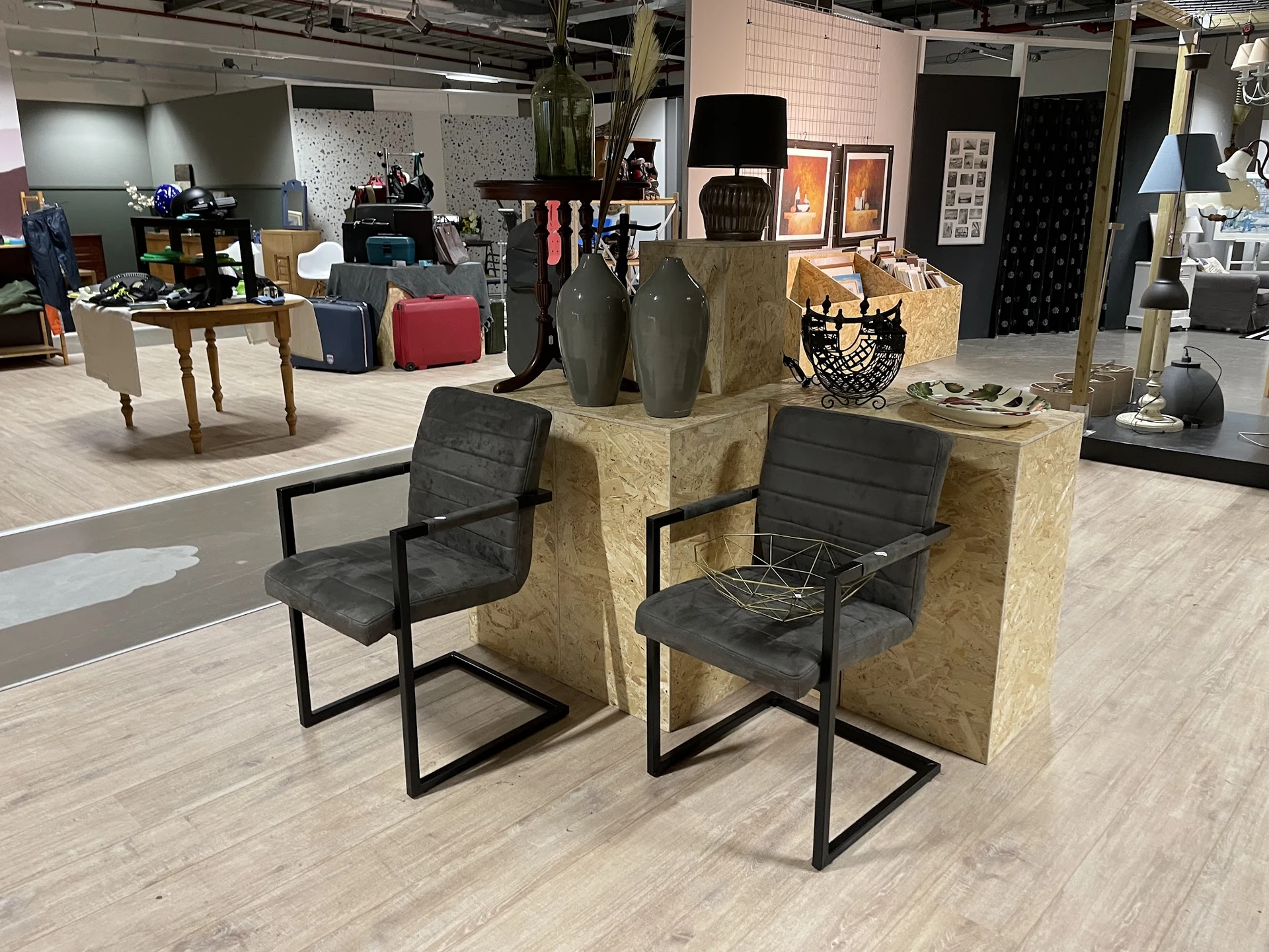 Tweedehands meubelen: zwarte stoelen met metalen frame rond gele/bruine kubusvormige elementen, met decoratieve items erop