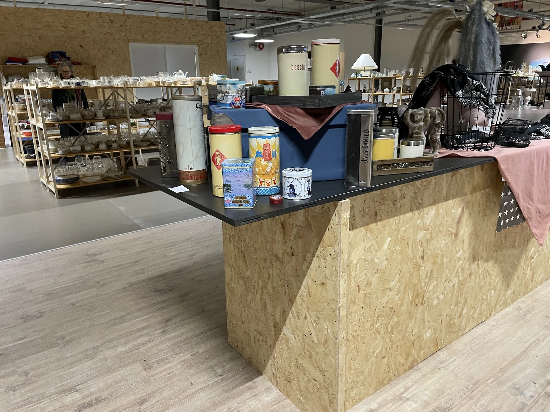 Winkelinterieur met houten toonbank en uiteenlopende spullen op planken en tafels