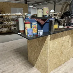 Winkelinterieur met houten toonbank en uiteenlopende spullen op planken en tafels