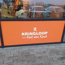 Oranje gevel van kringloopwinkel met wit logo en tekst 'KRINGLOOP voor Red een Kind'