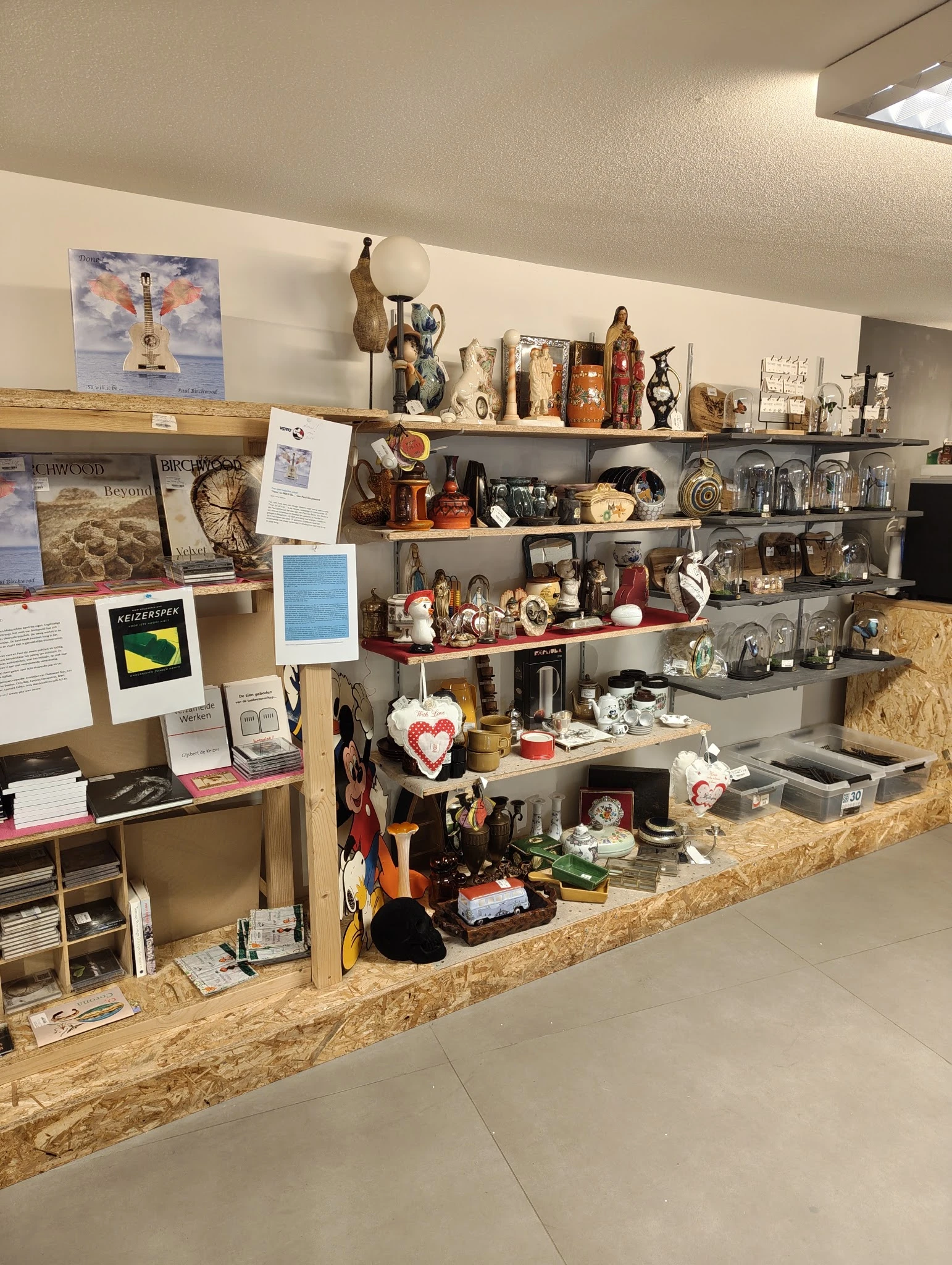 Stellingen vol met tweedehands spullen, beeldjes, decoratie-artikelen en huishoudgoederen in een kringloopwinkel