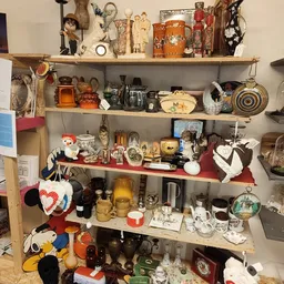 Houten wandplank met diverse tweedehands huishoudartikelen: servies, pannen, decoratieobjecten en keukenspullen