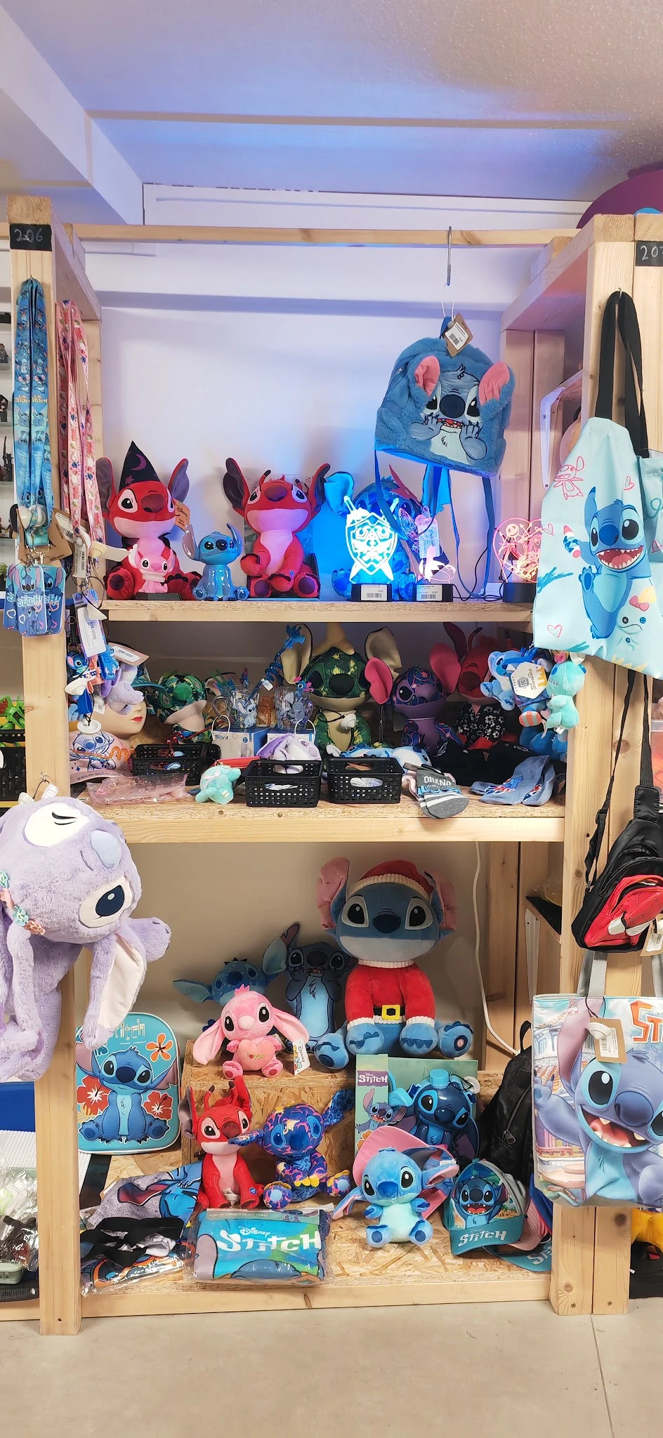 Houten stellingen vol met tweedehands speelgoed en decoraties, vooral blauwe en rode Stitch-figuren en accessoires