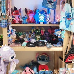 Houten stellingen vol met tweedehands speelgoed en decoraties, vooral blauwe en rode Stitch-figuren en accessoires