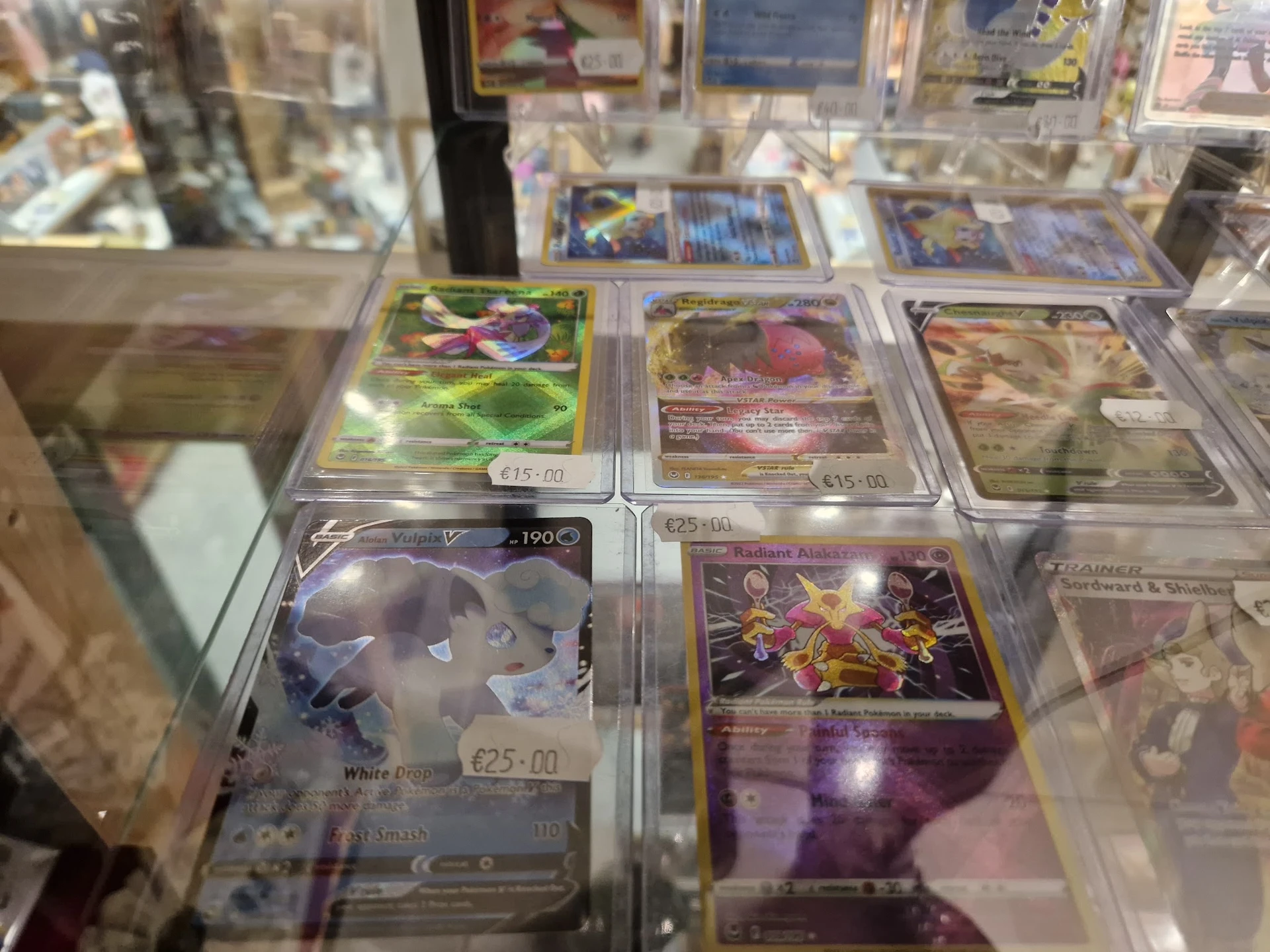 Vitrinekast met verzameling van in plastic hoesjes verpakte verzamelkaarten, waaronder Pokémon-kaarten met afbeeldingen van v