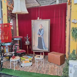 Uitstalkast met rood gordijn en portret, vintage meubels en decoratie in kringloopwinkel