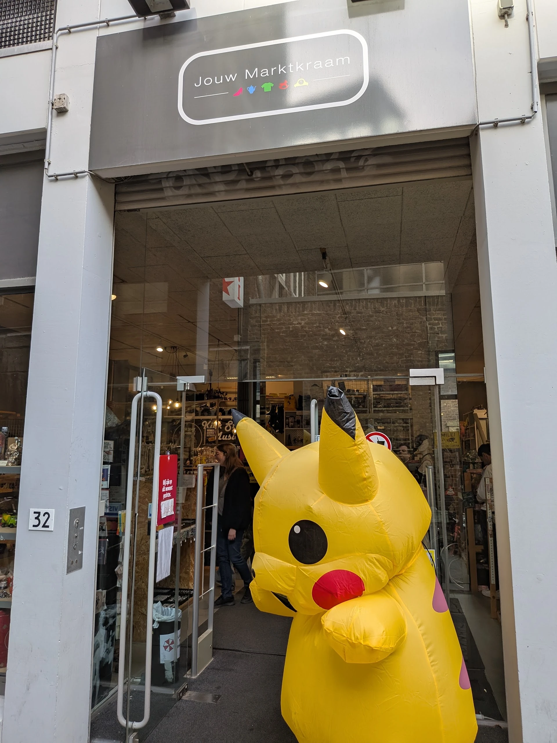 Winkelfront met grote gele Pikachu-figuur in de etalage en glazen deuren