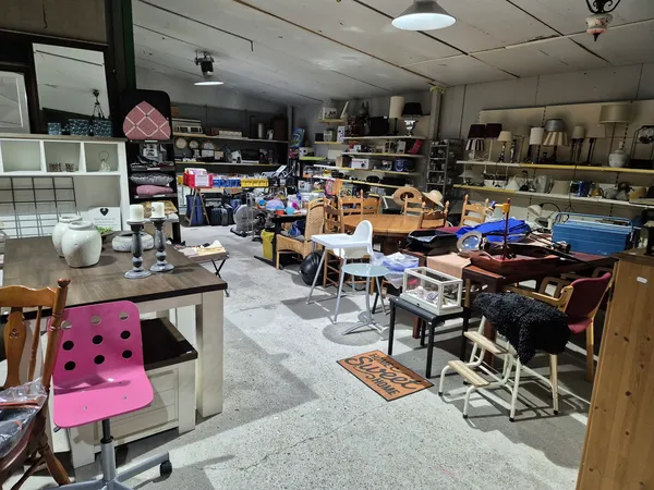 Overzicht van winkelinterieur met stellingen, meubels, stoelen en diverse spullen