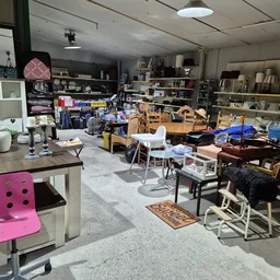 Overzicht van winkelinterieur met stellingen, meubels, stoelen en diverse spullen