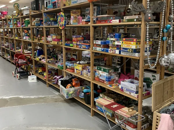 Houten stellingen vol met speelgoed, puzzels, spellen en diverse spullen in een kringloopwinkel