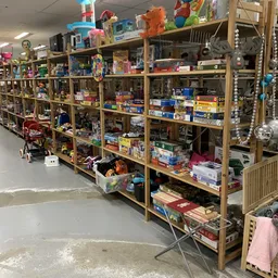 Houten stellingen vol met speelgoed, puzzels, spellen en diverse spullen in een kringloopwinkel