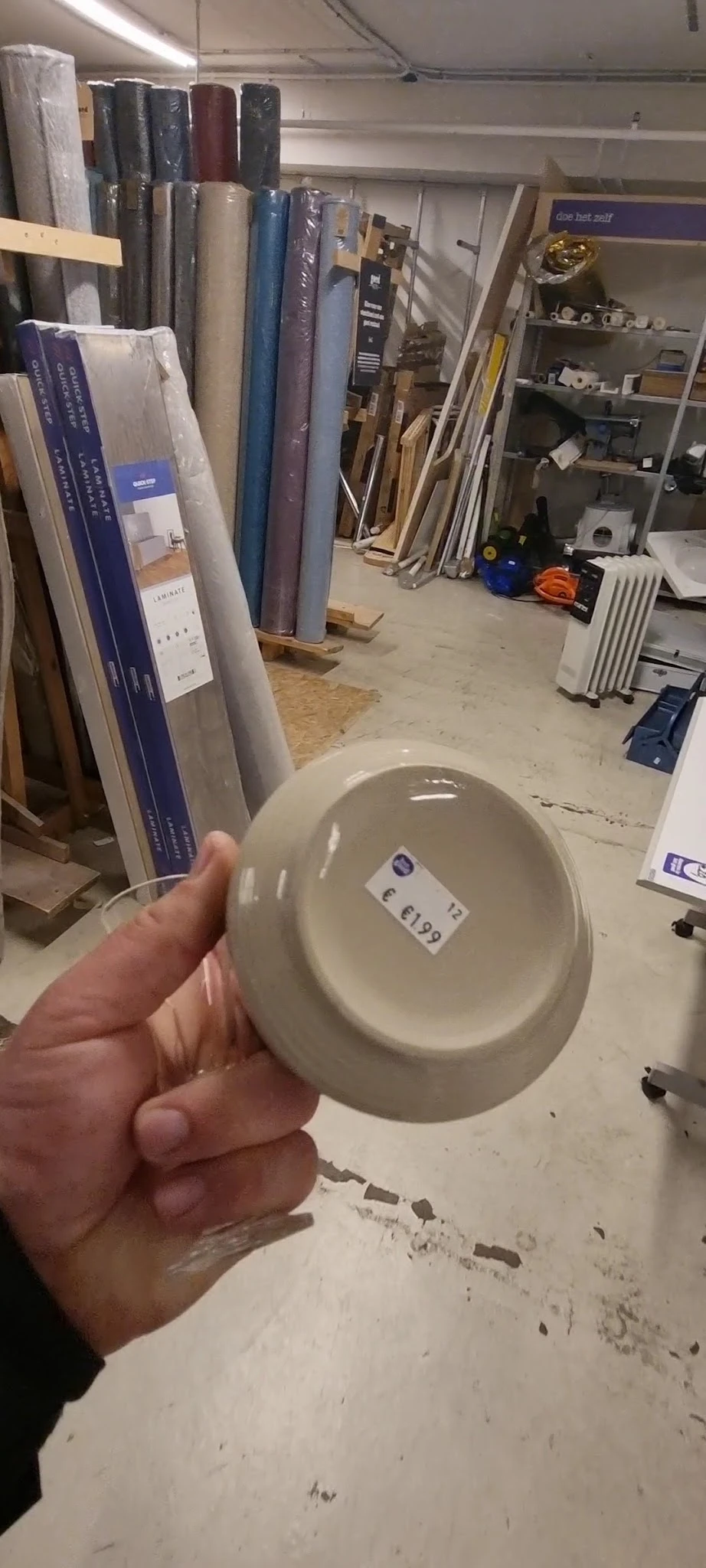 Hand houdt een witte keramische schaal vast met een prijssticker eraan