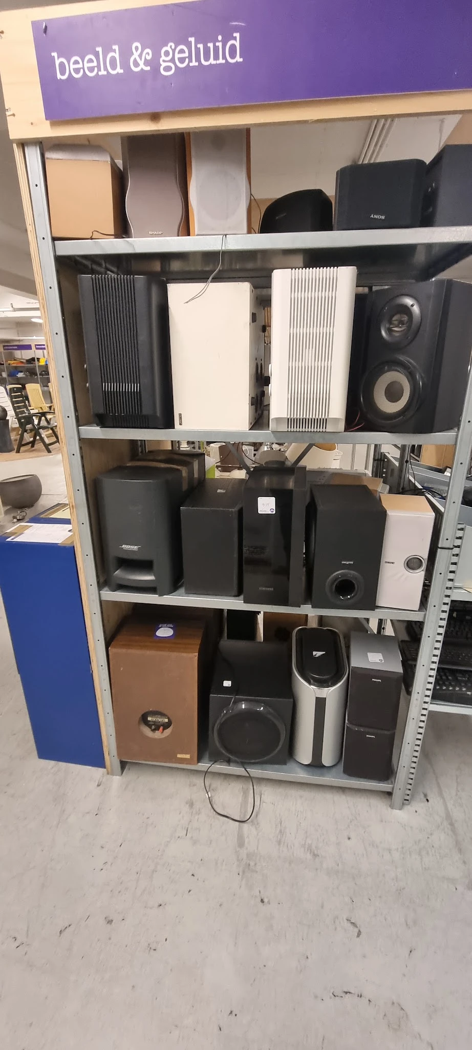 Stellingkasten met diverse zwarte en witte luidsprekers en audio-apparatuur uitgestald