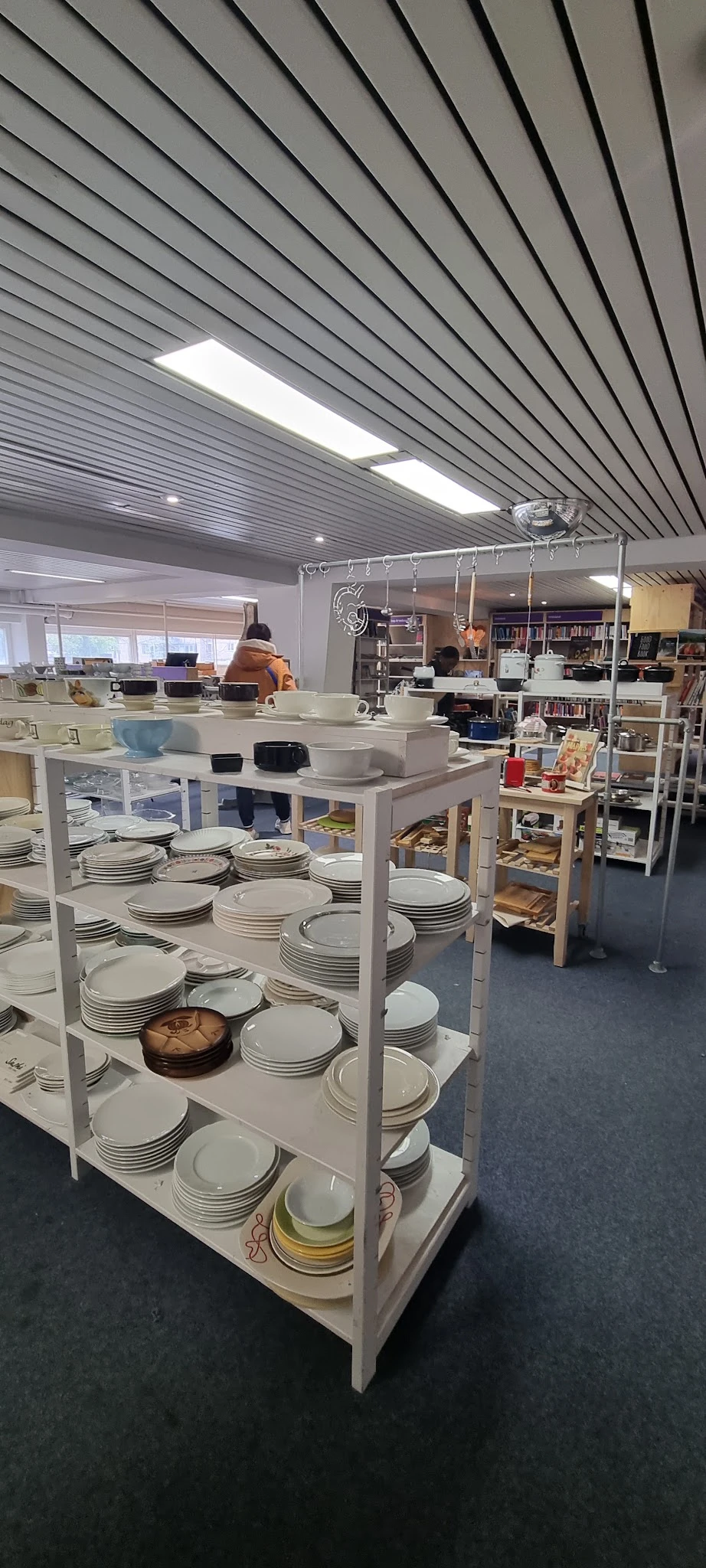 Tafels met grote hoeveelheden wit serviesgoed, borden en schalen in kringloopwinkel