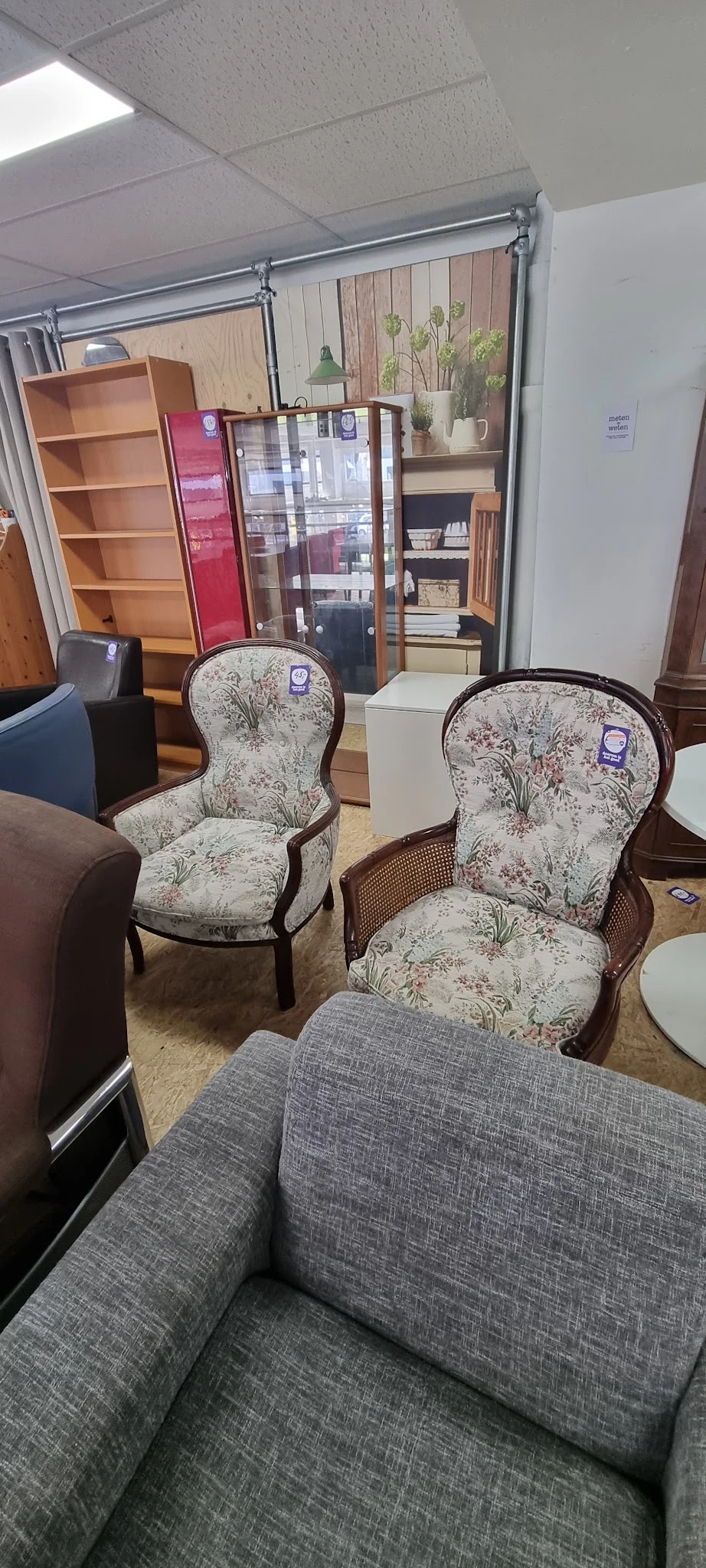 Twee klassieke fauteuils met bloemenmotief en houten frame in kringloopwinkel