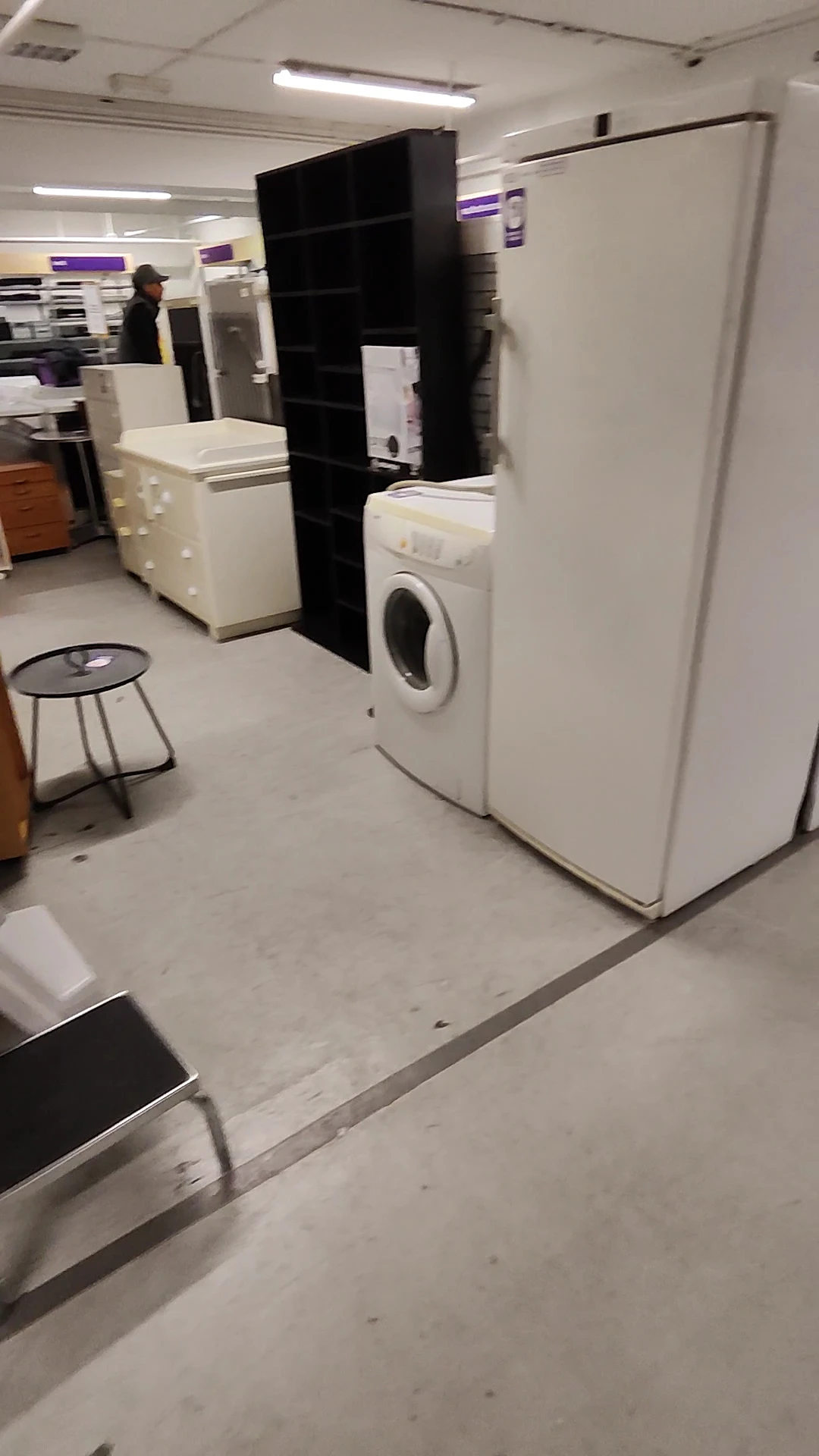 Winkelinterieur met witgoedapparaten zoals wasmachine en koelkast, kleine kruk op de vloer