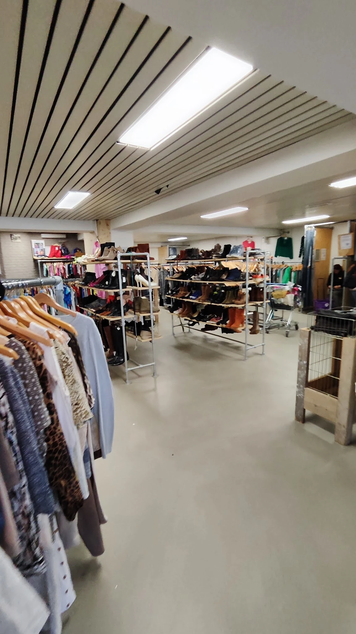 Winkelvloer met stellingen vol tweedehands kleding, schoenen en accessoires onder LED-verlichting