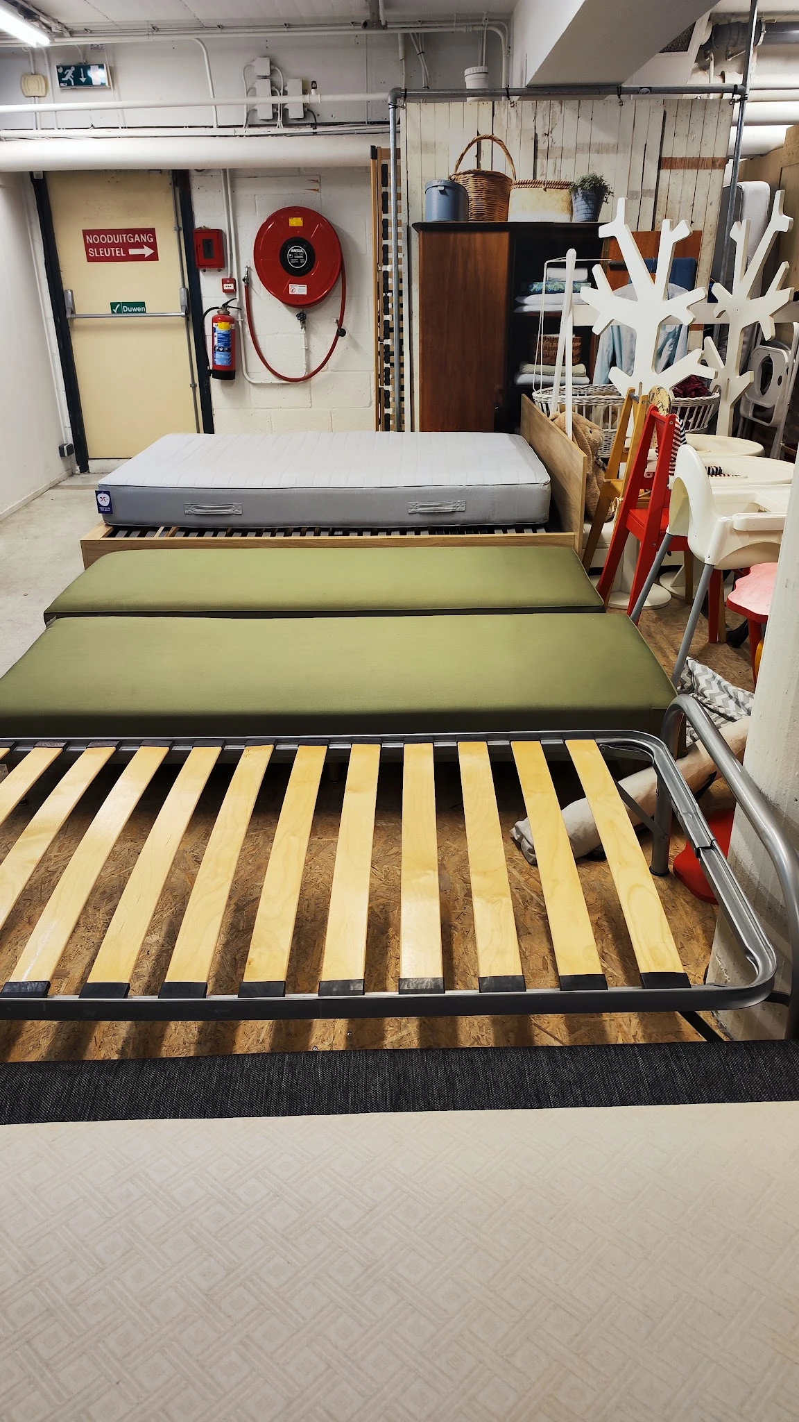 Gestapelde bedframes met lattenbodem en matrassen in verschillende kleuren