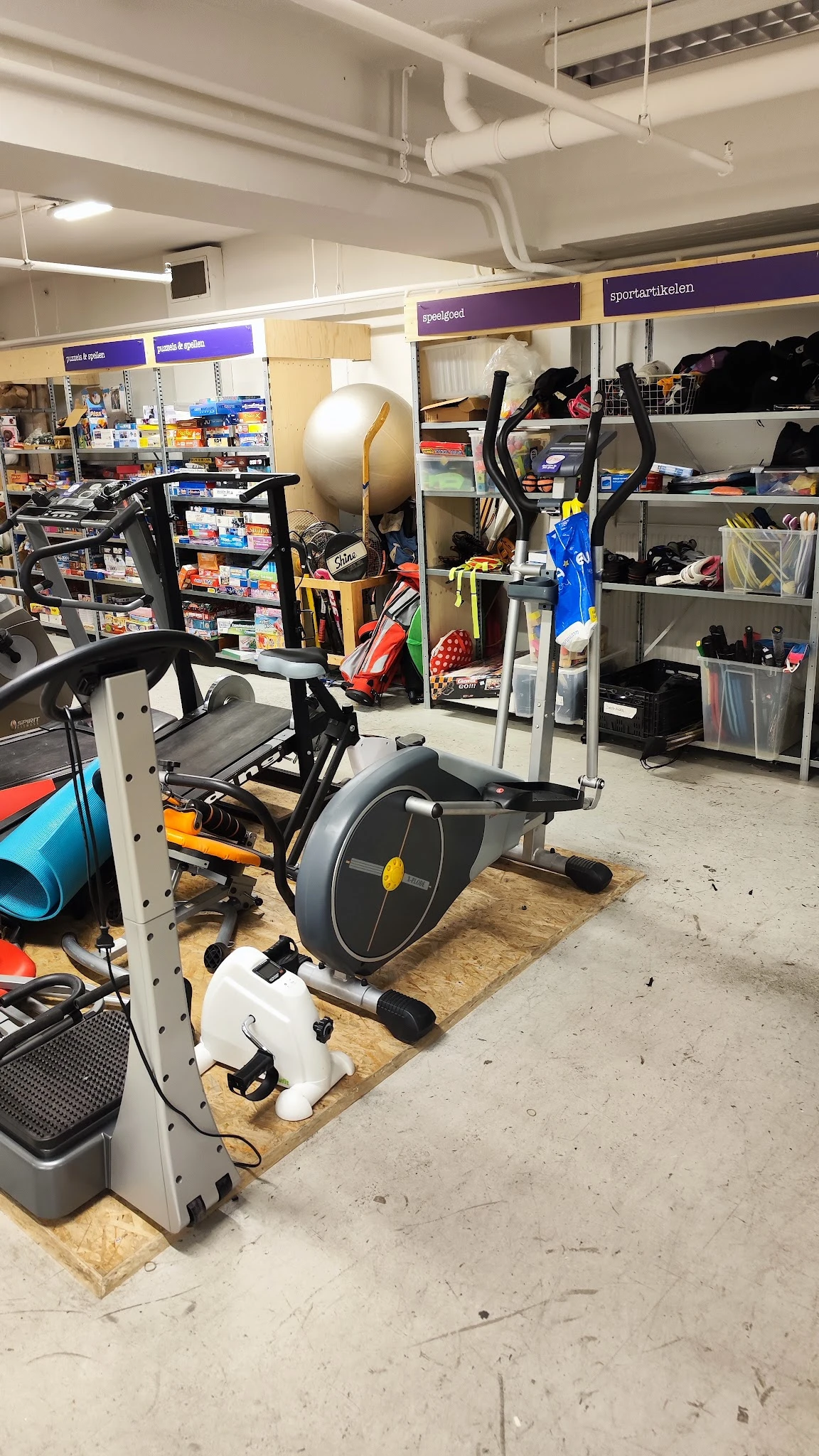 Hometrainer/spinningfiets met zwart en geel design op houten platform in werkplaats