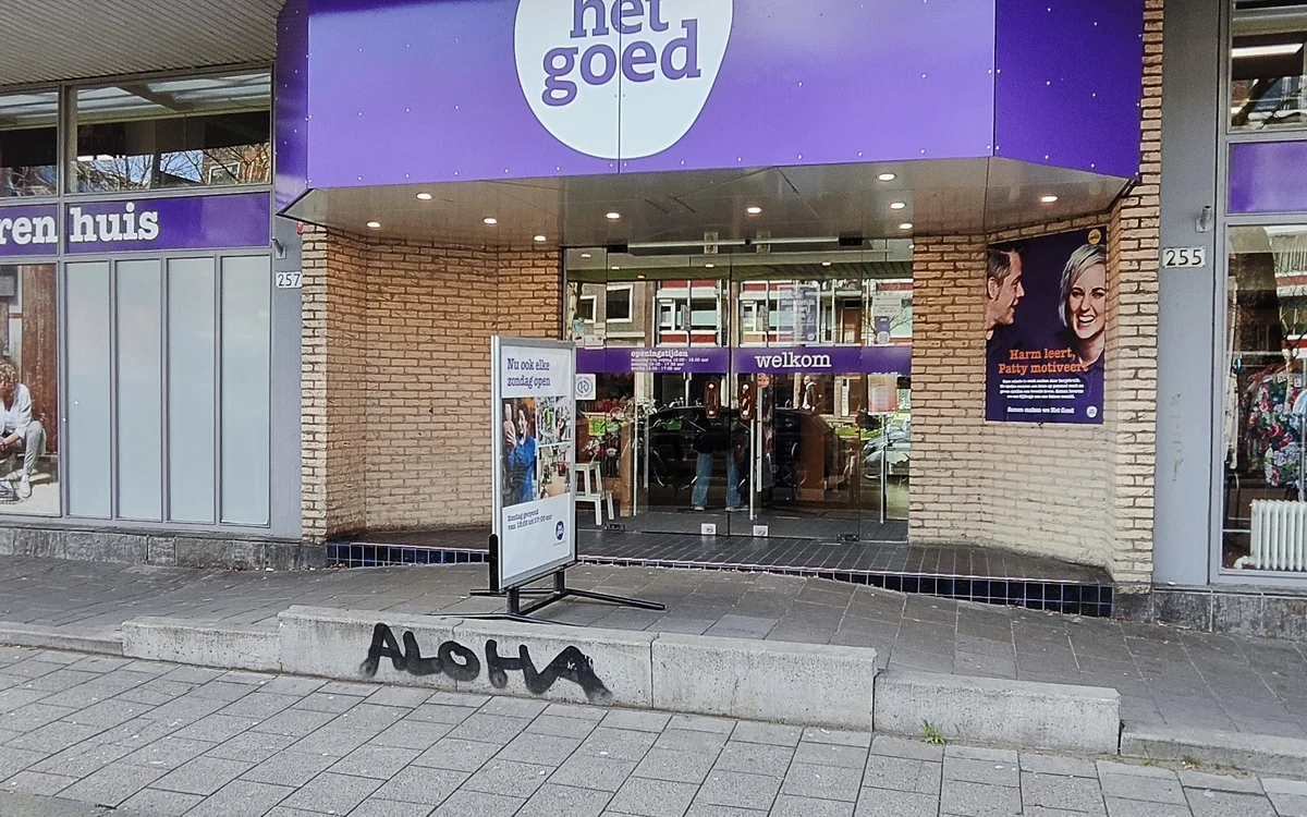 Paarse gevel van kringloopwinkel het goed aan Boergoensestraat met entree, ramen en welkomsttekst