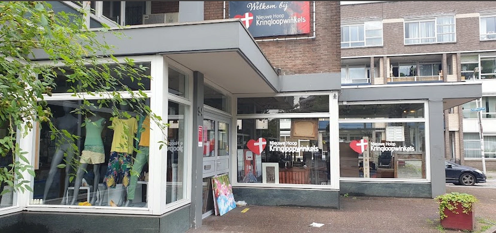 Voorkant van kringloopwinkel met witte pui, glazen deuren en ramen, winkelnaambord zichtbaar