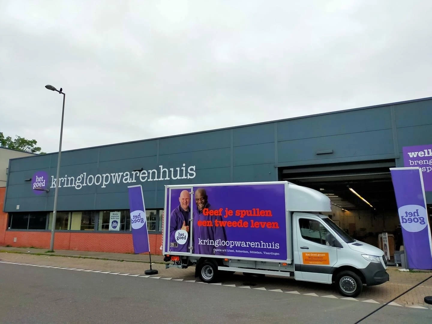 Bedrijfsbus met logo en naam van kringloopwinkel voor de gevel
