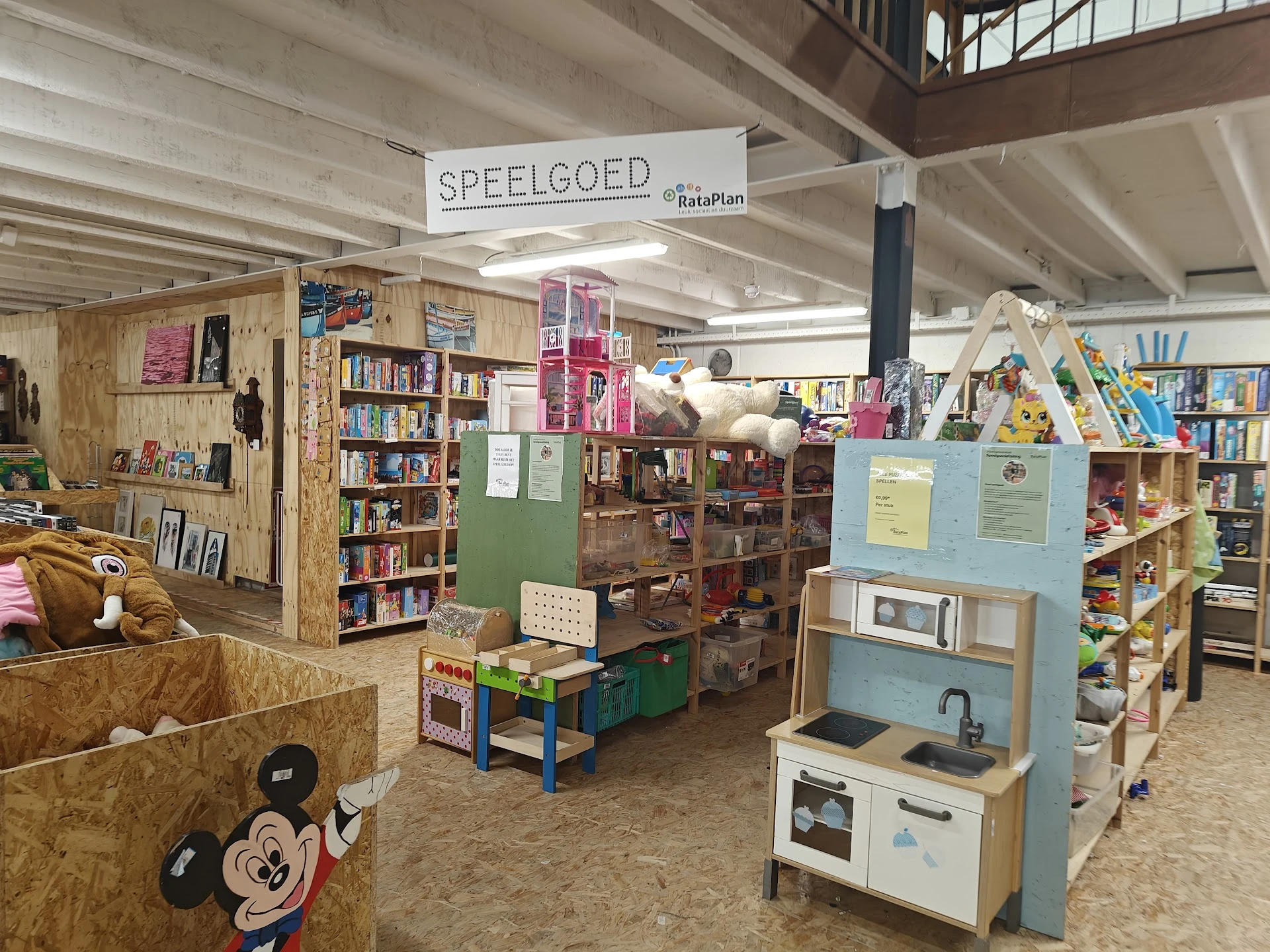 Kinderspeelhoek met speelgoedkeuken, boekenkasten en speelmateriaal in kringloopwinkel