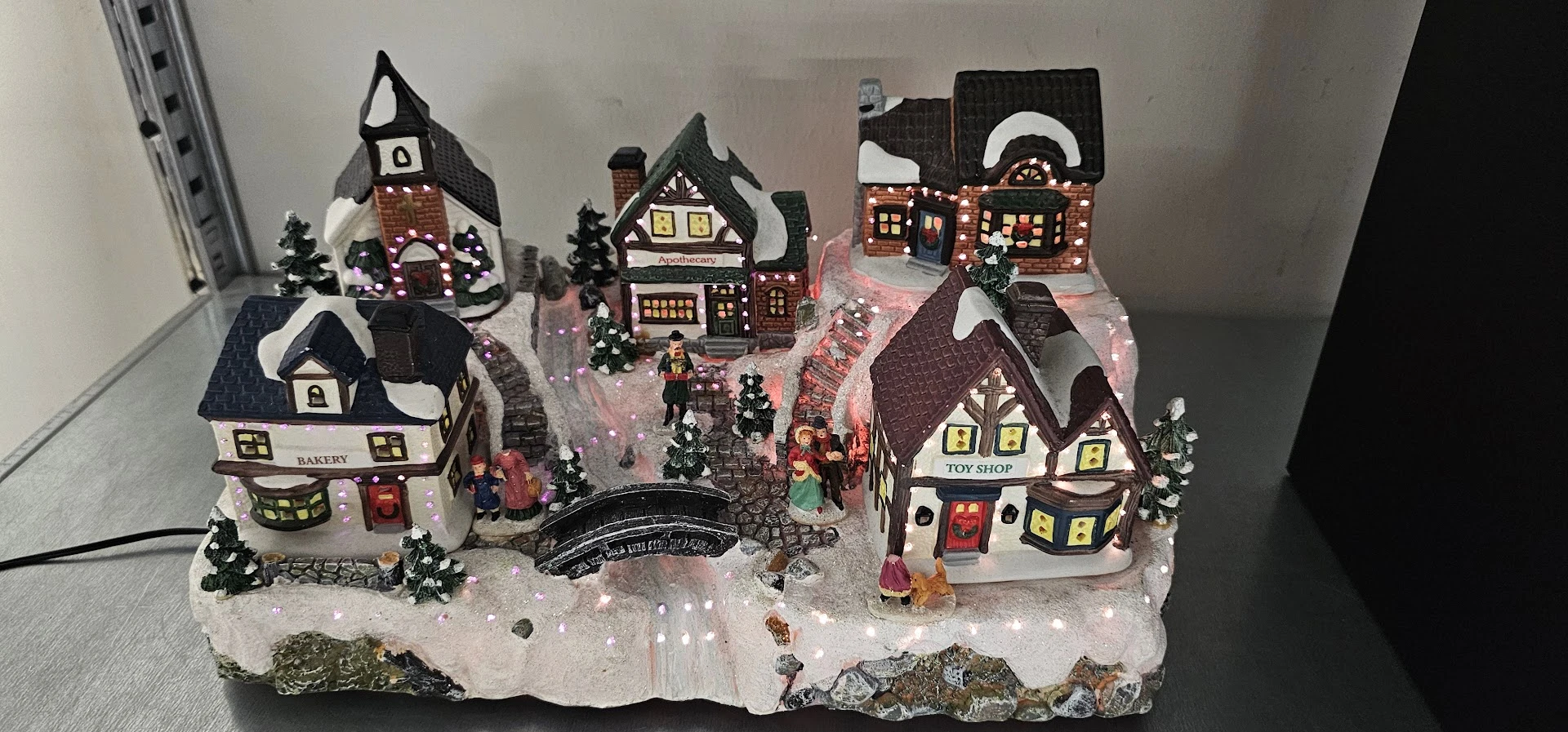 Miniatuurnstadje met kersthuisjes, kerkje, winkels en sneeuw onder ledverlichting